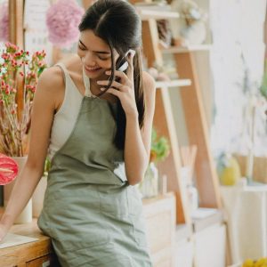 Florist on her phone, writing notes in her shop