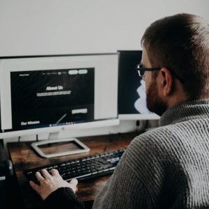 Man working on a website on a large monitor at his desk
