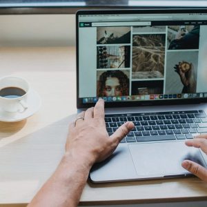 Hands on a laptop showing a website, with a cup of coffee on the desk